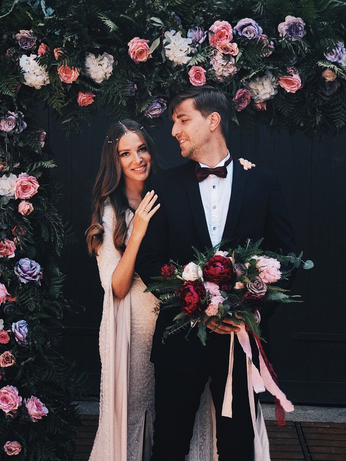The newlyweds celebrating beneath a floral installation